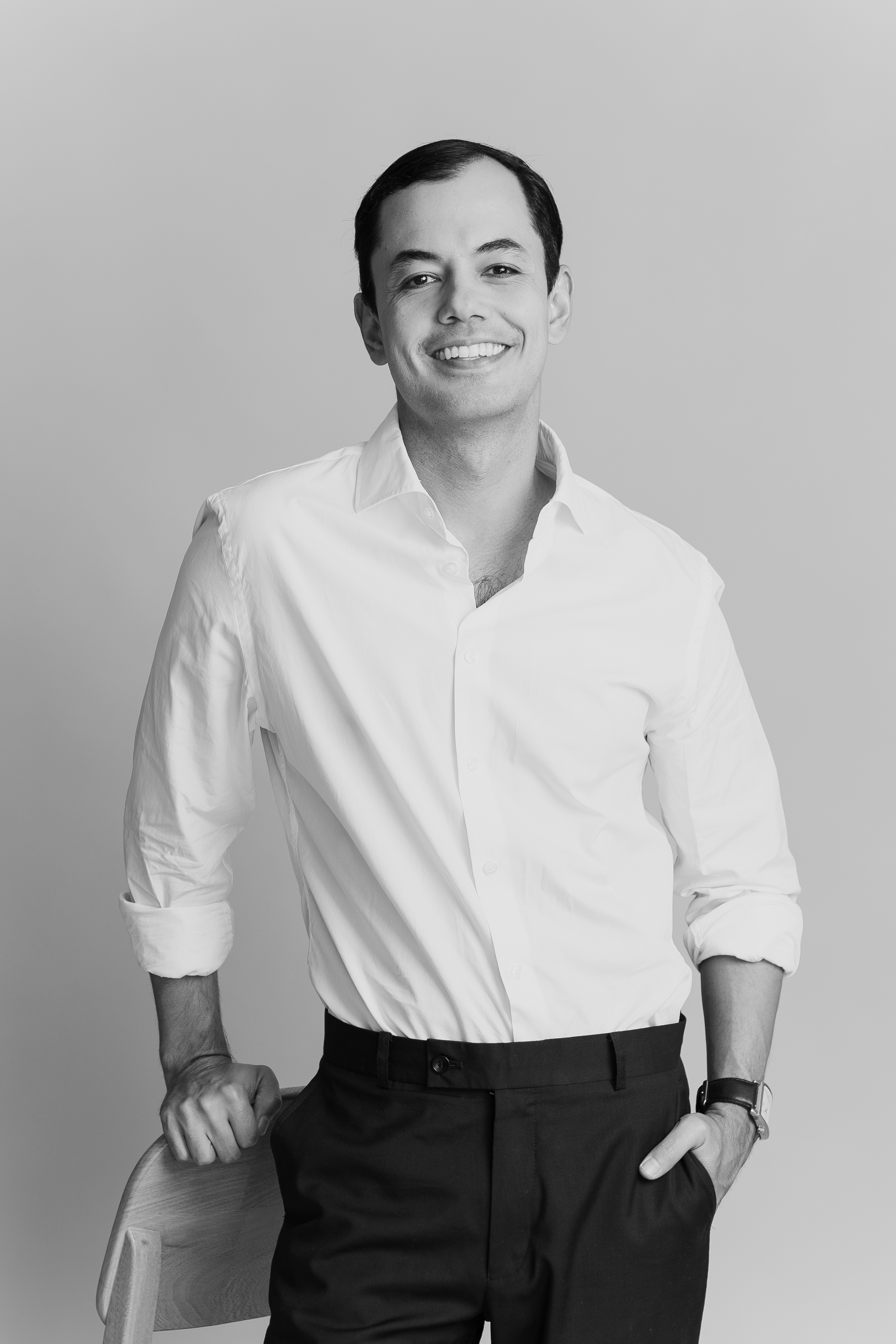 Julio Mario De León de pie, sonriendo con camisa blanca, en un retrato en blanco y negro